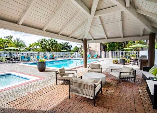 A patio with a pool and a white umbrella.
