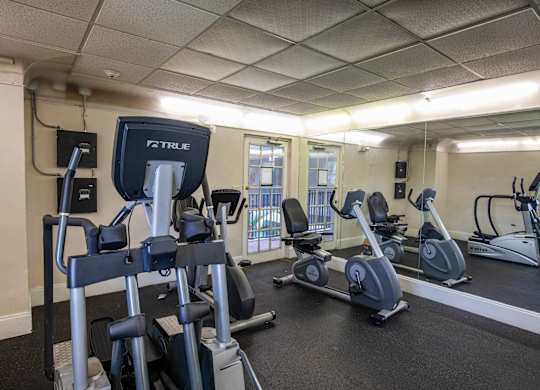 A gym with a variety of exercise equipment including treadmills, stationary bikes, and elliptical machines.
