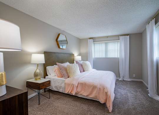 A bedroom with a bed, nightstand, and lamp.