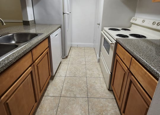 a kitchen with white appliances and wooden cabinets at Sunscape Apartment Homes, Tampa, 33613