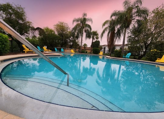 a swimming pool with palm trees and chairs around it at Sunscape Apartment Homes, Tampa, FL, 33613