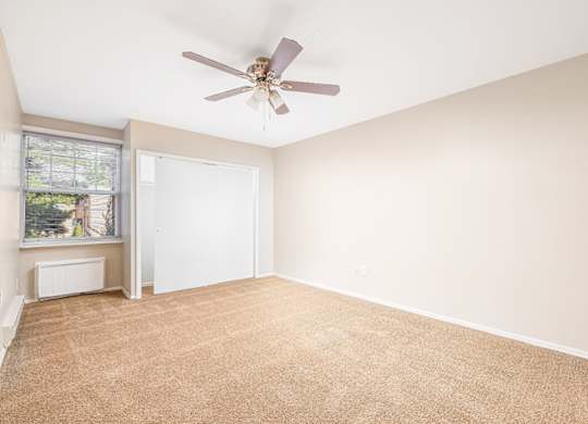A room with a ceiling fan and carpeted floor.