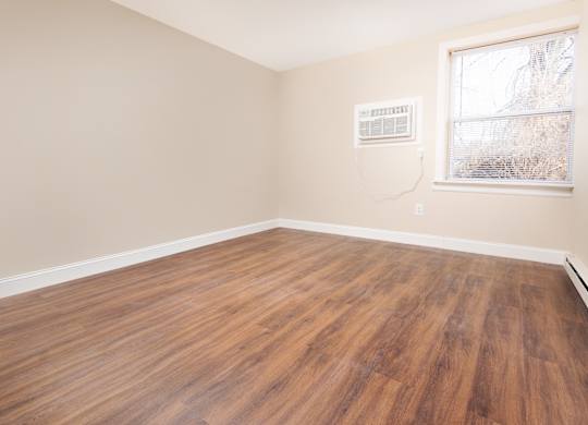 Empty room with wooden flooring and a window.