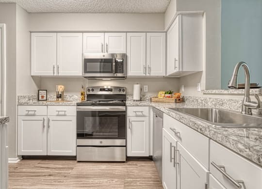 A kitchen with white cabinets and a marble countertop.