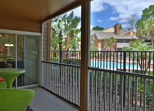 A green chair is on a patio with a pool in the background.