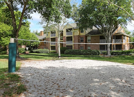 A sandy area in front of a building with a green pole on each side.