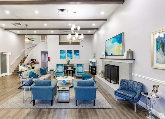 a living room with blue chairs and a fireplace  at The Park at Chesterfield Apartment Homes, Tampa, FL, 33617