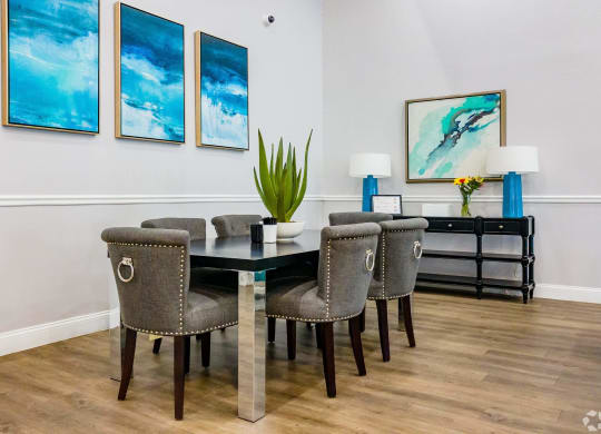 a dining room with a table and chairs and paintings on the wall  at The Park at Chesterfield Apartment Homes, Tampa