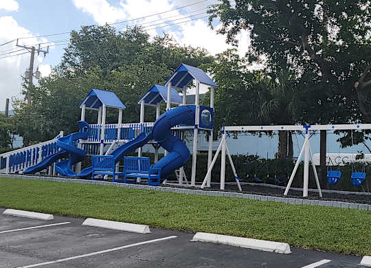 a playground with a blue slide in a parking lot