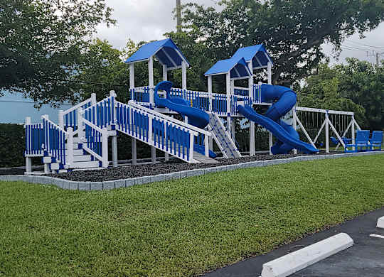 a playground with a blue set of slides in a parking lot