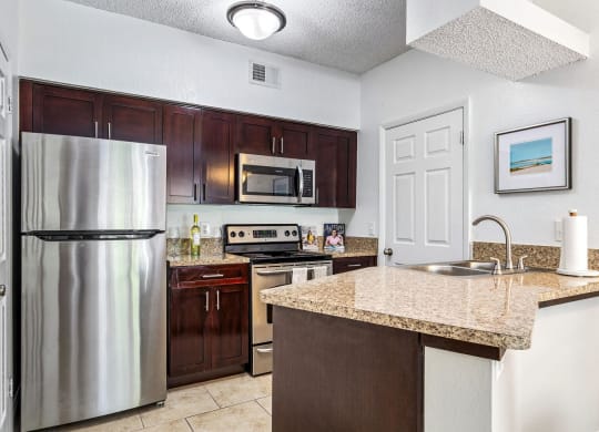 a kitchen with stainless steel appliances and a granite counter top at Waterford Park Apartment Homes, LLC, Florida