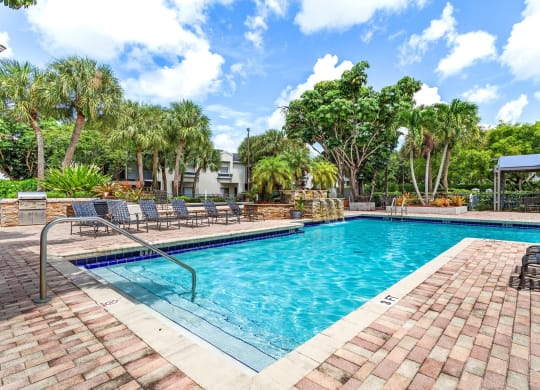 a swimming pool with trees and chairs around it at Waterford Park Apartment Homes, LLC, Lauderhill, FL 33319