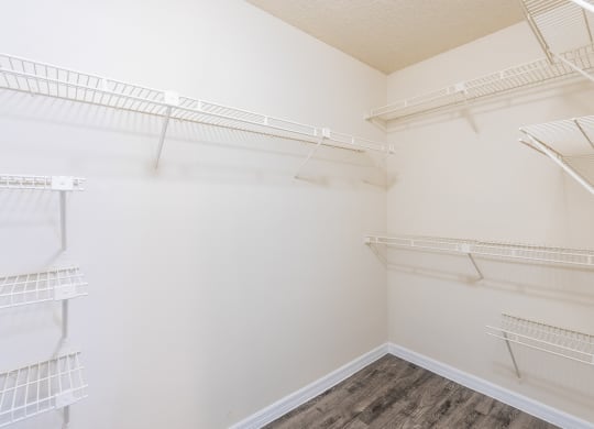 a spacious walk in closet with white walls and shelves and mirrored closet doors  at Fisherman's Landing Apartment Homes, Tampa, Florida