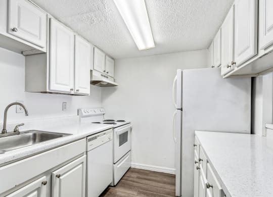 a kitchen with white cabinets and a sink and a refrigerator at Greenwich Commons Apartment Homes, Tampa, FL, 33613
