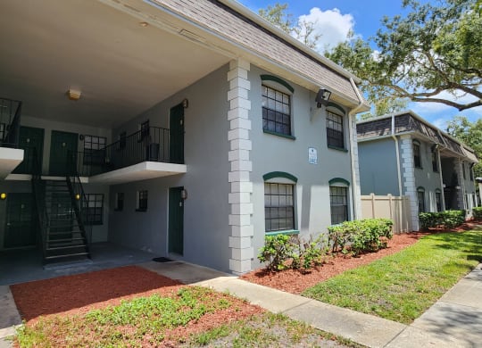 the front of a white house with a yard and a staircase at Greenwich Commons Apartment Homes, Tampa, FL