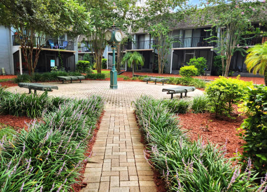 a courtyard with benches and a clock at Greenwich Commons Apartment Homes, Florida
