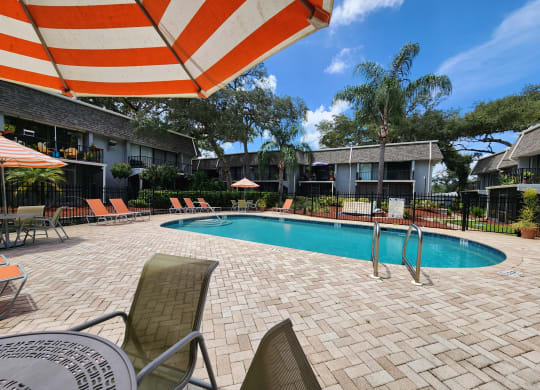 a swimming pool with chairs and an umbrella at a hotel at Greenwich Commons Apartment Homes, Florida