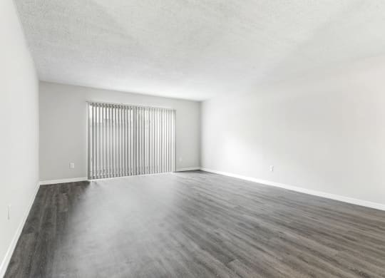 an empty living room with white walls and wood floors at Greenwich Commons Apartment Homes, Florida