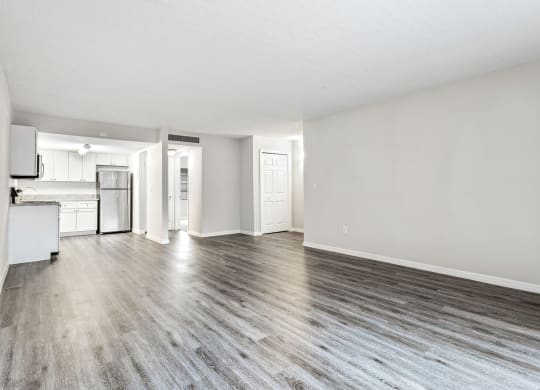 an empty living room and kitchen with white walls and wood floors at Greenwich Commons Apartment Homes, Tampa, FL, 33613