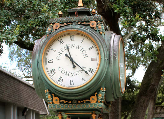 a green clock on a pole in a park at Greenwich Commons Apartment Homes, Tampa, Florida