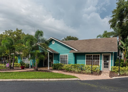 a blue house with palm trees in front of it at Madison Oaks Apartment Homes, LLC, Palm Harbor Florida