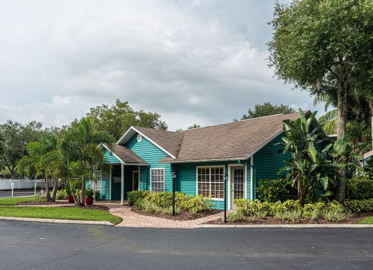 a green house with trees and a road in front of it at Madison Oaks Apartment Homes, LLC, Palm Harbor, FL 34684