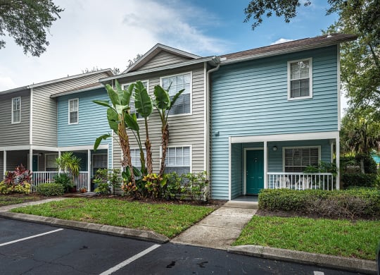 a blue house with palm trees in front of it at Madison Oaks Apartment Homes, LLC, Palm Harbor