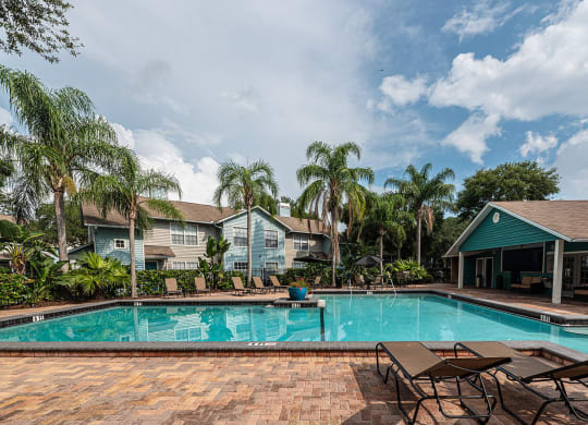 a swimming pool with chairs and houses in the background at Madison Oaks Apartment Homes, LLC, Florida