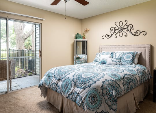 a bedroom with a bed and a sliding glass door at Madison Oaks Apartment Homes, LLC, Palm Harbor, FL 34684