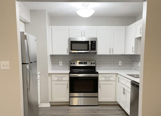 a kitchen with stainless steel appliances and white cabinets at Madison Oaks Apartment Homes, LLC, Palm Harbor, FL