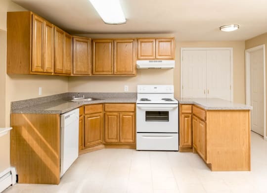 a kitchen with white appliances and wooden cabinets at Raritan Crossing Apartment Homes, New Jersey