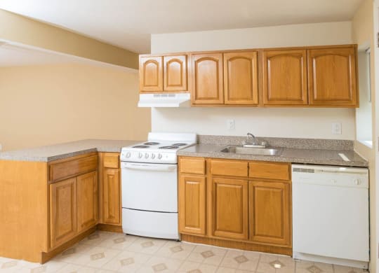 a kitchen with white appliances and wooden cabinets at Raritan Crossing Apartment Homes, New Brunswick New Jersey