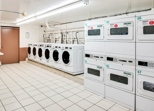 a row of white washing machines in a laundry room at Raritan Crossing Apartment Homes, New Brunswick, NJ
