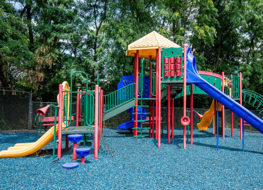 a colorful playground with slides and other toys at Raritan Crossing Apartment Homes, New Brunswick, NJ 08901