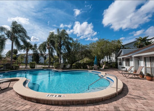 a swimming pool with chairs and a house in the background at Sunscape Apartment Homes, Tampa, 33613