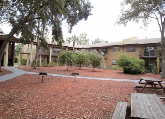 a courtyard with picnic tables and benches in front of an apartment building  at Oak Manor Apartment Homes, Tampa, FL, 33617