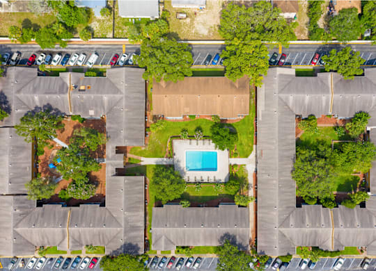 An aerial view of a parking lot with a swimming pool in the middle.
