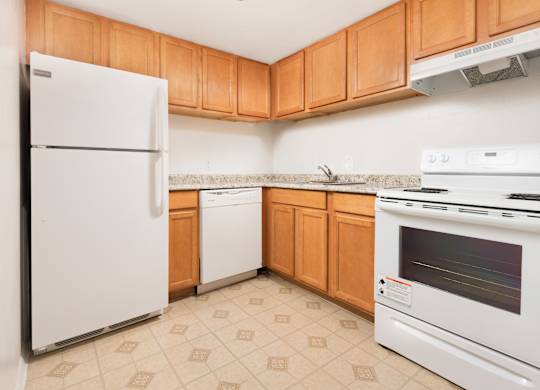 A kitchen with a white refrigerator, dishwasher, and oven.