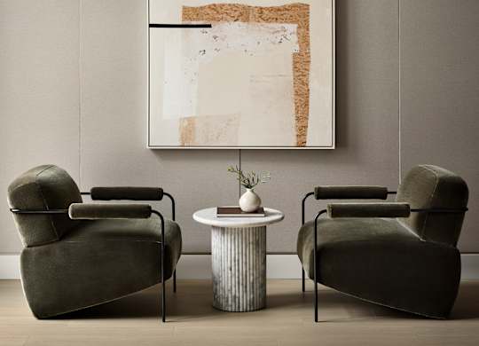Two chairs and a table are in front of a framed artwork.