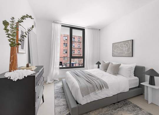 A bedroom with a large bed, a dresser, and a window with a view of a building outside.
