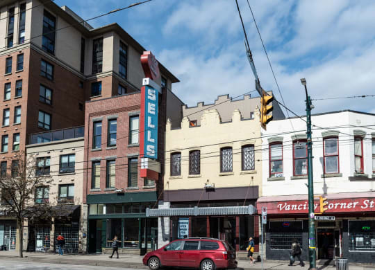 a view of a street corner with a red car parked in front of a building