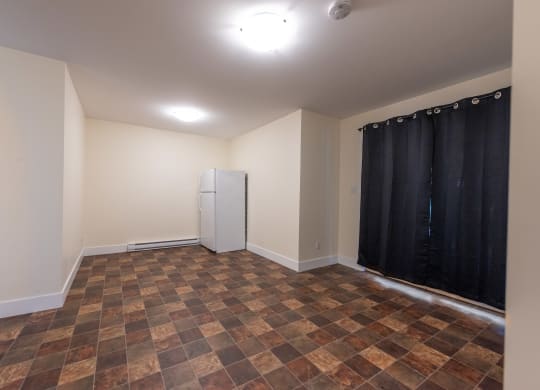 an empty room with a refrigerator in the corner