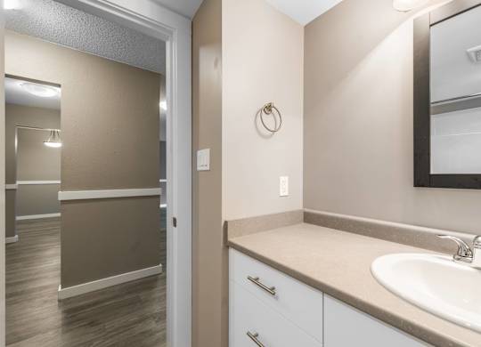 A bathroom with a sink, mirror, and cabinets.