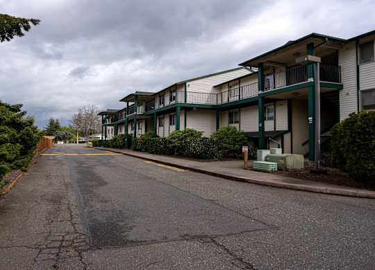 A street view of apartment buildings with a cloudy sky.