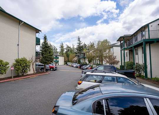 A parking lot with cars parked in front of apartment buildings.
