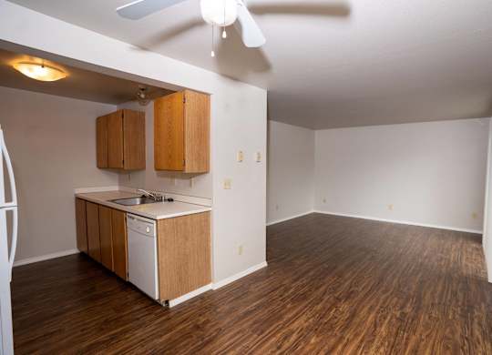 A kitchen with wooden floors and a ceiling fan.