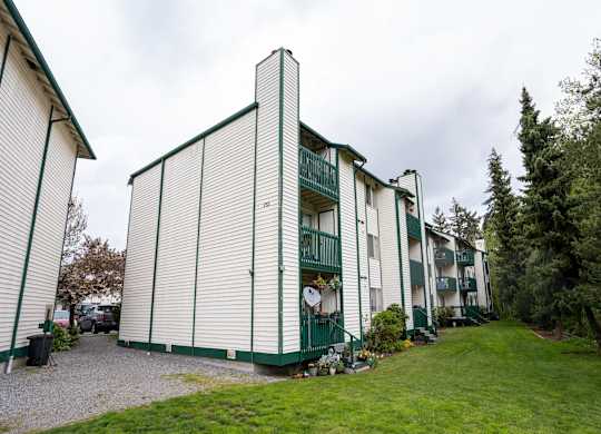 A white and green building with a green lawn in front.