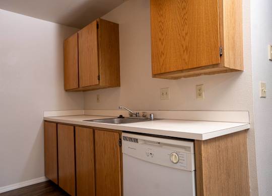 A small kitchen with a washing machine and wooden cabinets.