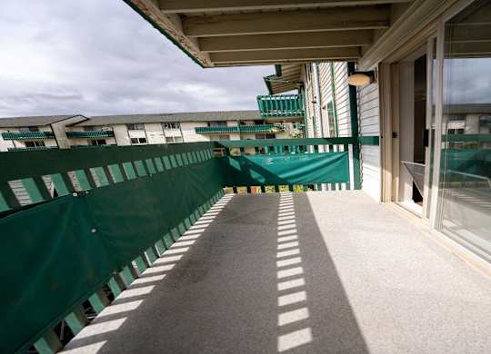A balcony with a green railing and a concrete floor.