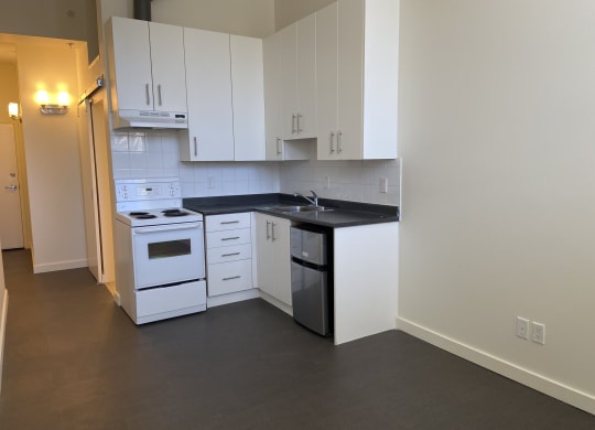 a kitchen with white cabinets and black countertops